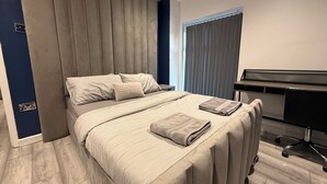 Un dormitorio moderno con una cama grande, un escritorio y una ventana con persianas.