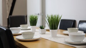 Una mesa de comedor con platos blancos, cuencos y pequeñas macetas.