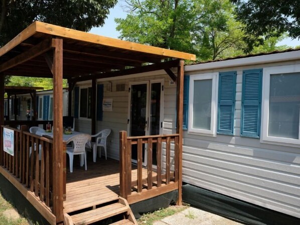 A covered outdoor seating area with a wooden deck and a table with chairs.