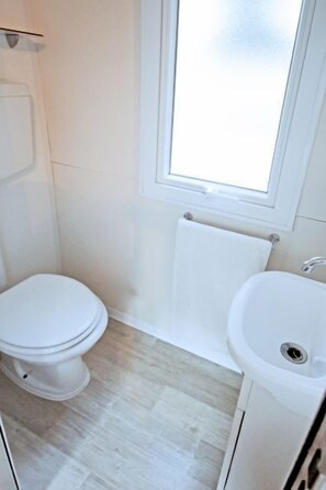 A small, clean bathroom with a toilet, sink, and a window above the sink.