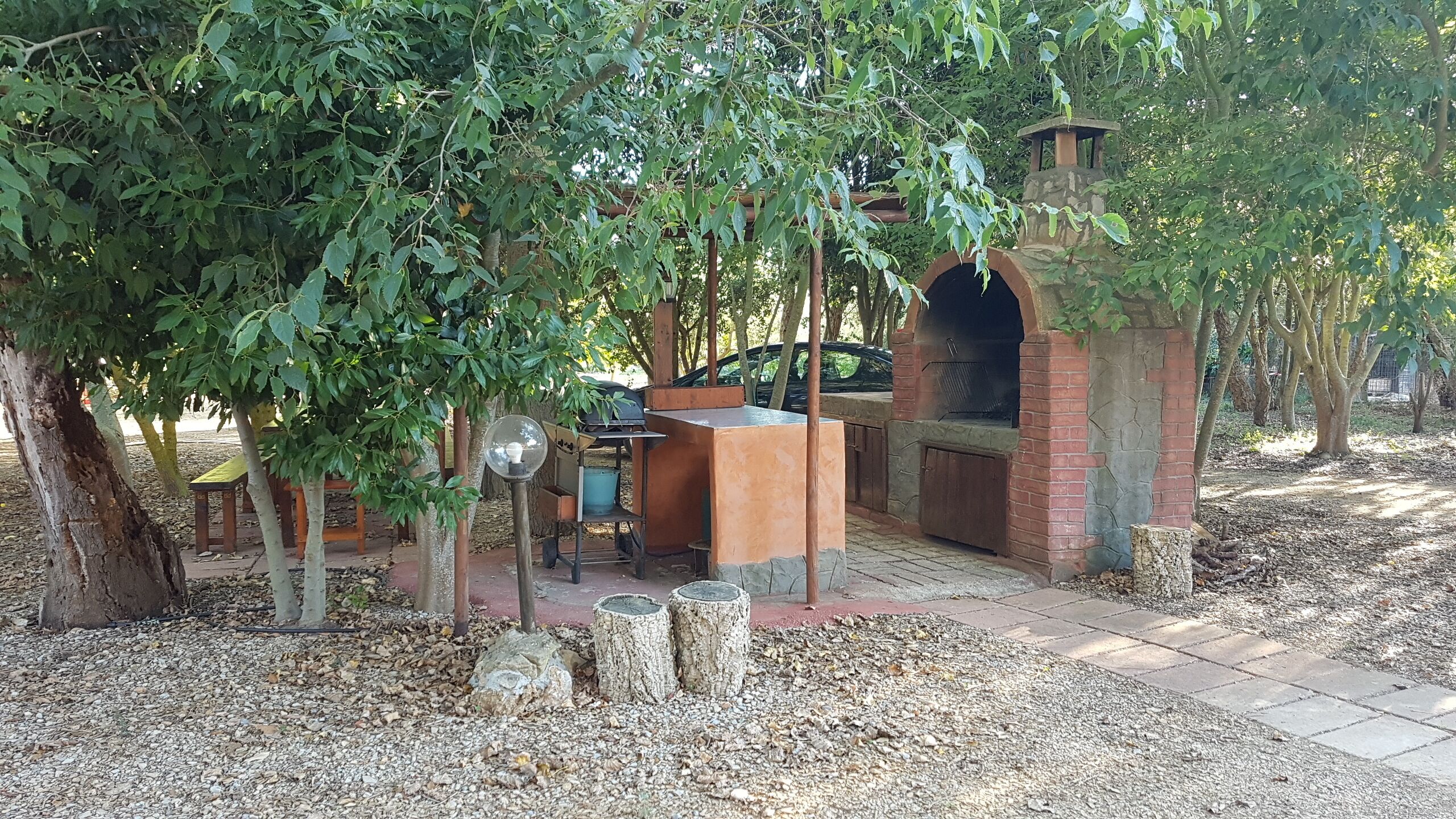 An outdoor patio area with a brick barbecue, seating, and a pergola.