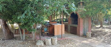 An outdoor patio area with a brick barbecue, seating, and a pergola.