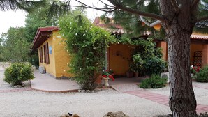A yellow building with a red roof, surrounded by gravel paths and greenery. - Agriturismo La Barca In Secca (Olmedo)