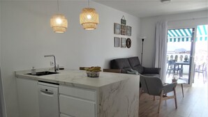 Eine moderne Küche mit einer Marmorinsel, weißen Schränken und einem Essbereich mit grauem Sofa und Stühlen.