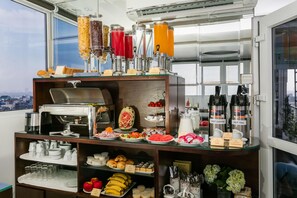 A buffet setup with various food items, a coffee machine, and hot beverage dispensers.