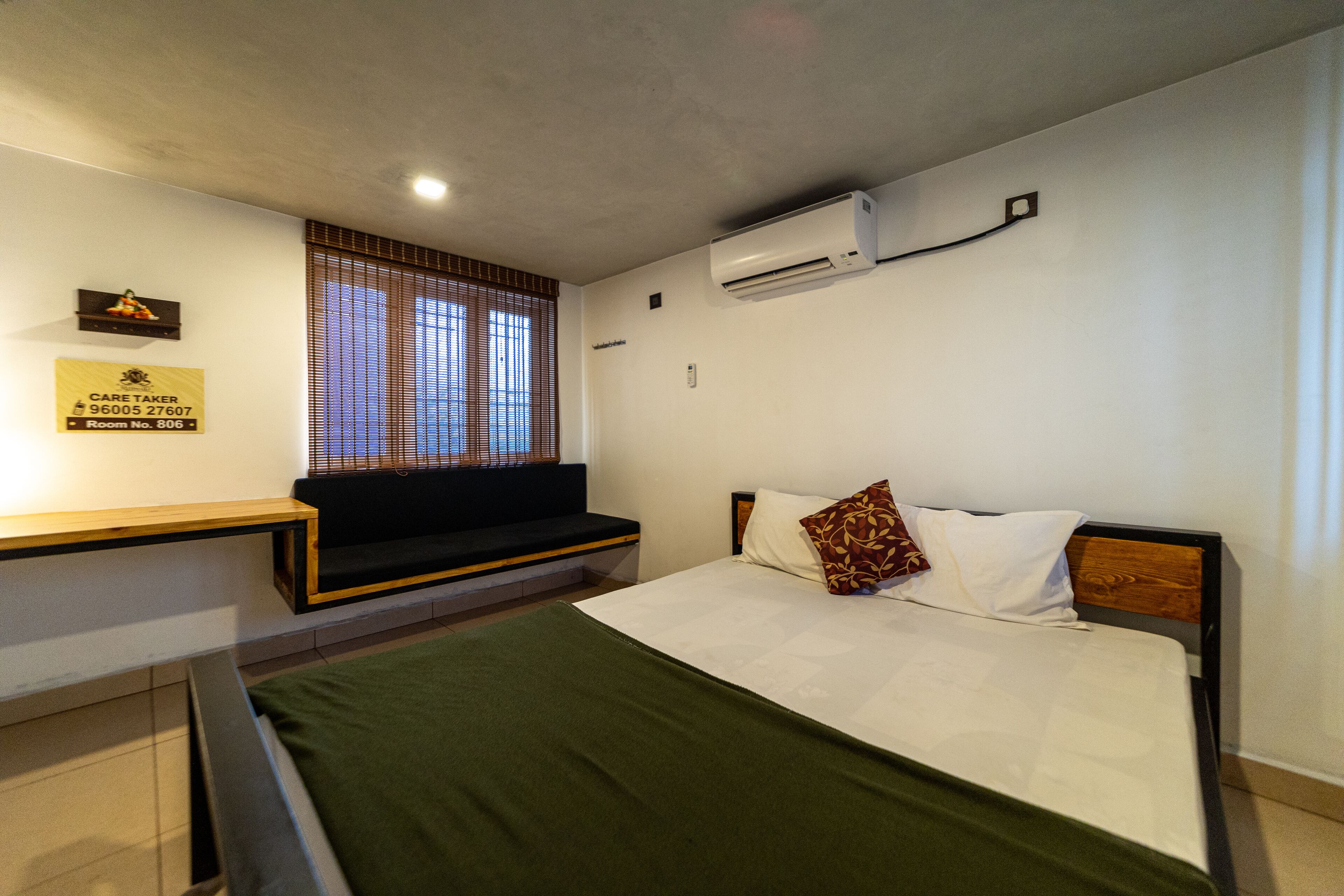 A bedroom with a bed, a bench, and a window with blinds.
