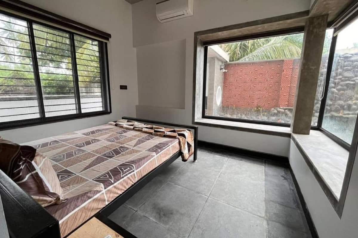 A bedroom with a bed, a window, and a remote control on a table.