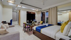 A hotel room with a large bed, a desk with a chair, a TV, and a balcony with curtains. - BlueNeck Sec 47 near Medanta -The Medicity' Gurugram (Gurugram)