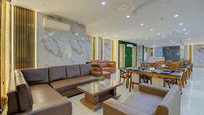 A spacious hotel lobby with a large seating area, a dining table, and a green accent wall. - BlueNeck Sec 47 near Medanta -The Medicity' Gurugram (Gurugram)