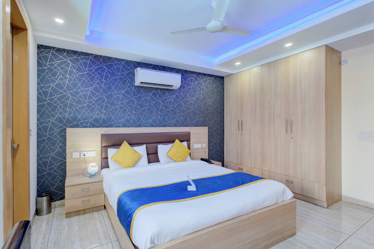 A modern bedroom with a bed, nightstands, a wardrobe, and an air conditioning unit.