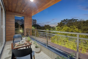 A balcony with a wooden ceiling, a glass table with chairs, and potted plants. - BlueNeck Sec 47 near Medanta -The Medicity' Gurugram (Gurugram)