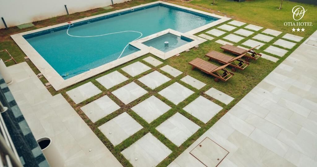 A swimming pool with a tiled deck, a small hot tub, and lounge chairs.