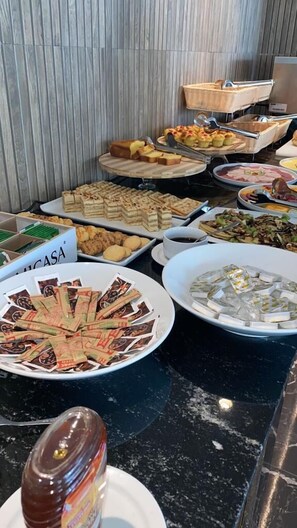 A buffet with various food items including pastries, sandwiches, and a bowl of ice cream.