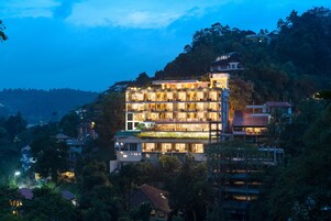 Un hotel de varios pisos con un diseño moderno, que cuenta con balcones y amplias ventanas.