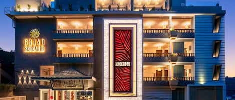Ein modernes Hotel mit auffälligem Schild, mehreren Balkonen und einer gut beleuchteten Fassade.