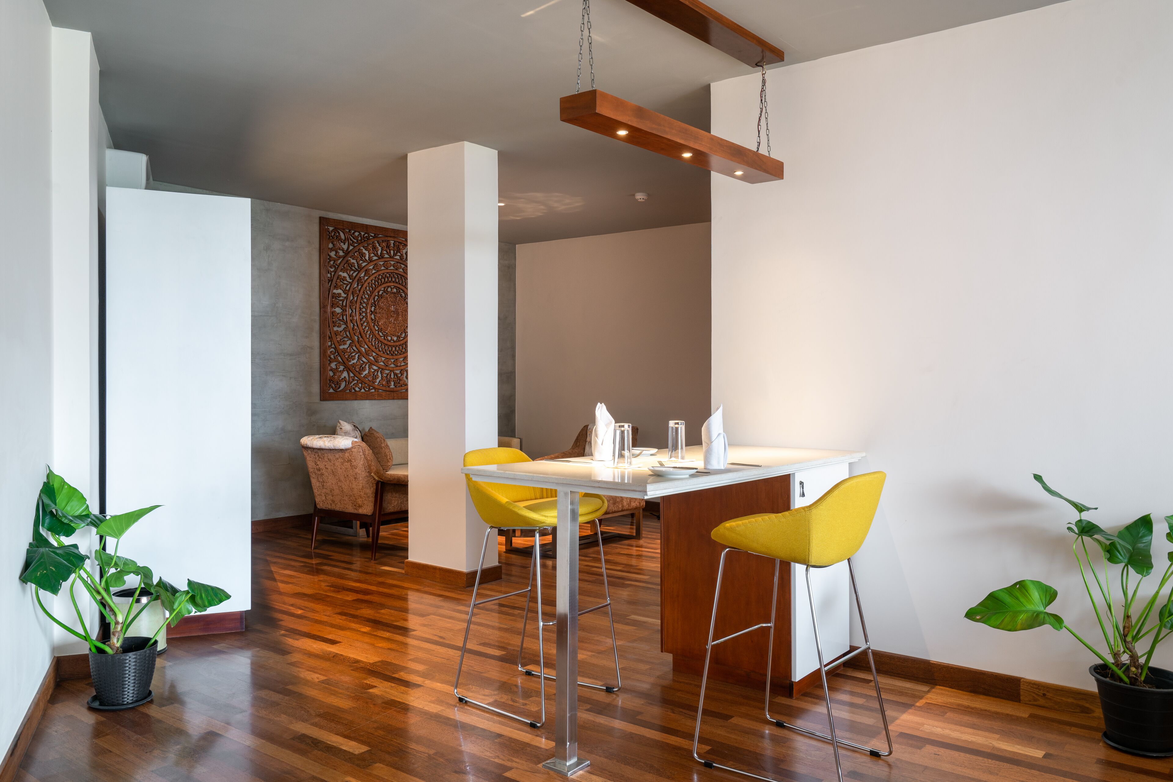 A modern dining area with a wooden ceiling, a white table, and yellow chairs.