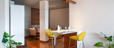 A modern dining area with a wooden ceiling, a white table, and yellow chairs.