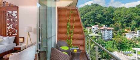 A balcony with a wooden floor, a sofa, a chair, and a small table with a yellow object.