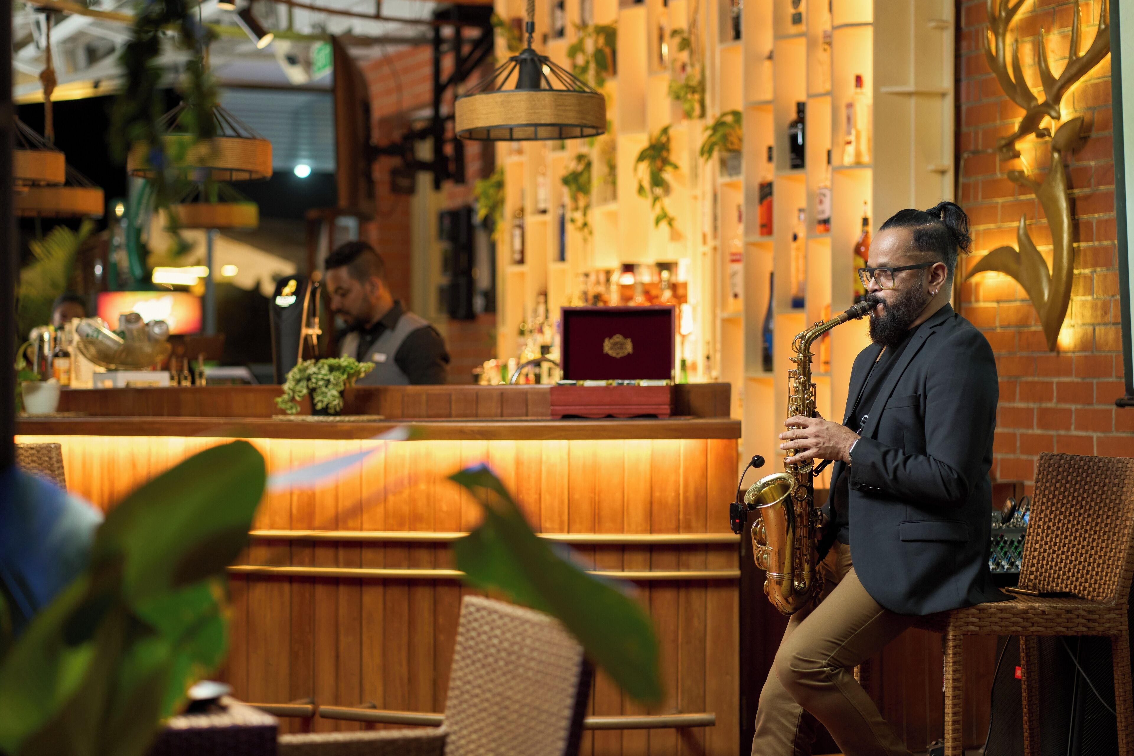 A jazz musician performing at a bar with wooden decor and a brick wall.