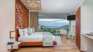 A modern bedroom with a large bed, a TV, and a city view.
