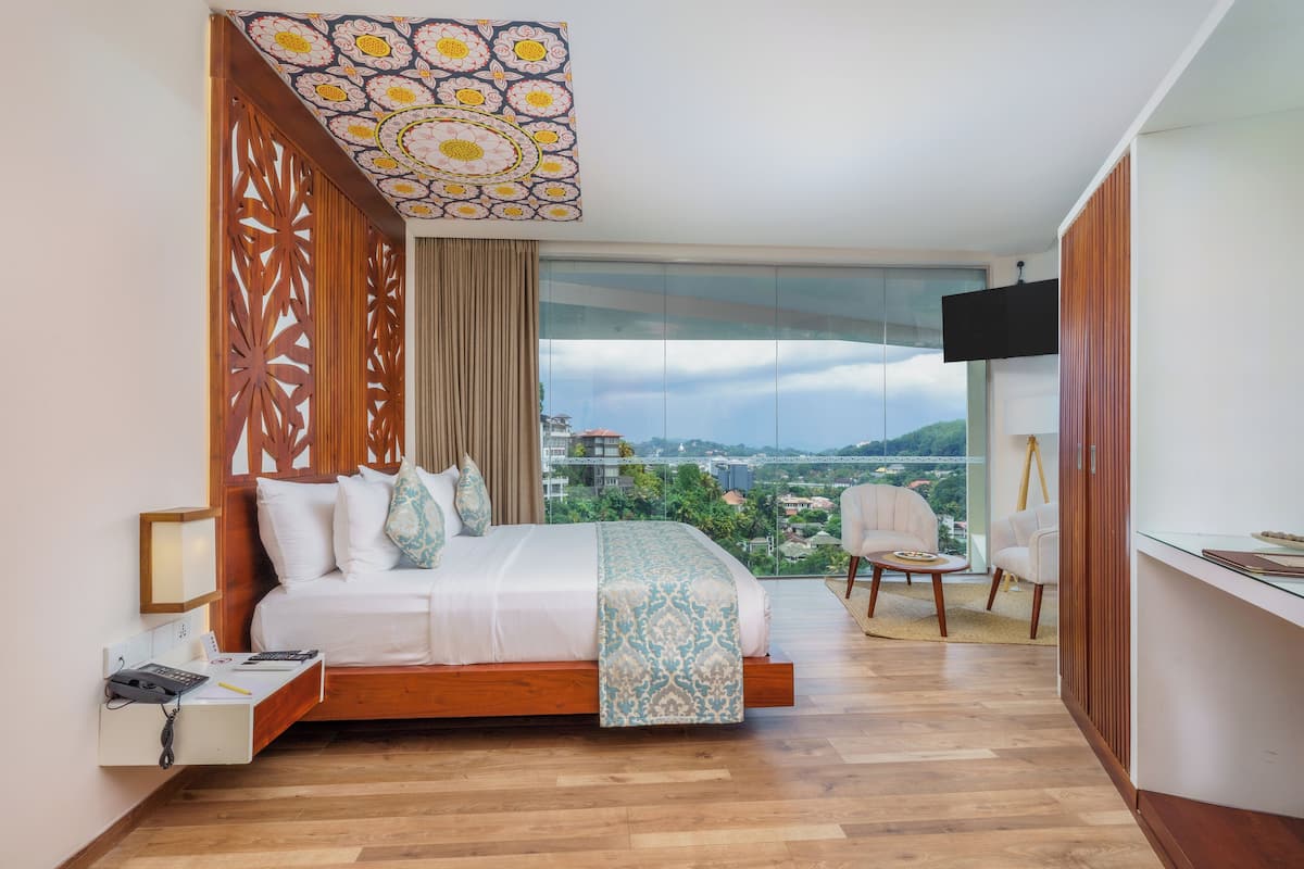 A modern bedroom with a large bed, a TV, and a city view.