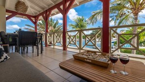 A covered outdoor seating area with a wooden table, two wine glasses, and a tray of stones. - Tropical Treasure |Sunset Penthouse Near Jan Thiel (Willemstad)