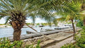 A marina with boats docked, a wooden walkway, and a hammock. - Tropical Treasure |Sunset Penthouse Near Jan Thiel (Willemstad)