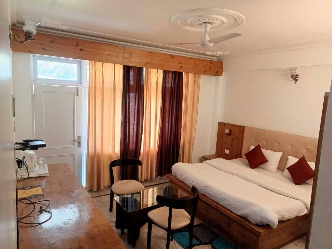 Una habitación con cama, escritorio, silla y ventilador de techo.