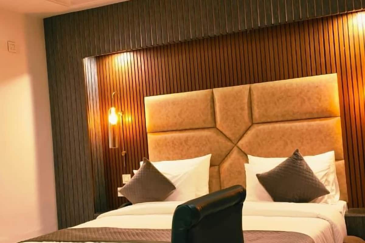 Een slaapkamer met een bed, een stoel, een tafel, een plafondventilator en wandlampen.