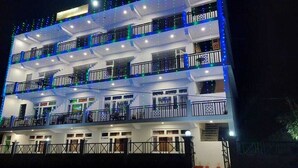 A multi-story hotel with balconies, each with a railing and a small window. - Hotel Sunshine Dharamshala (Dharamshala)