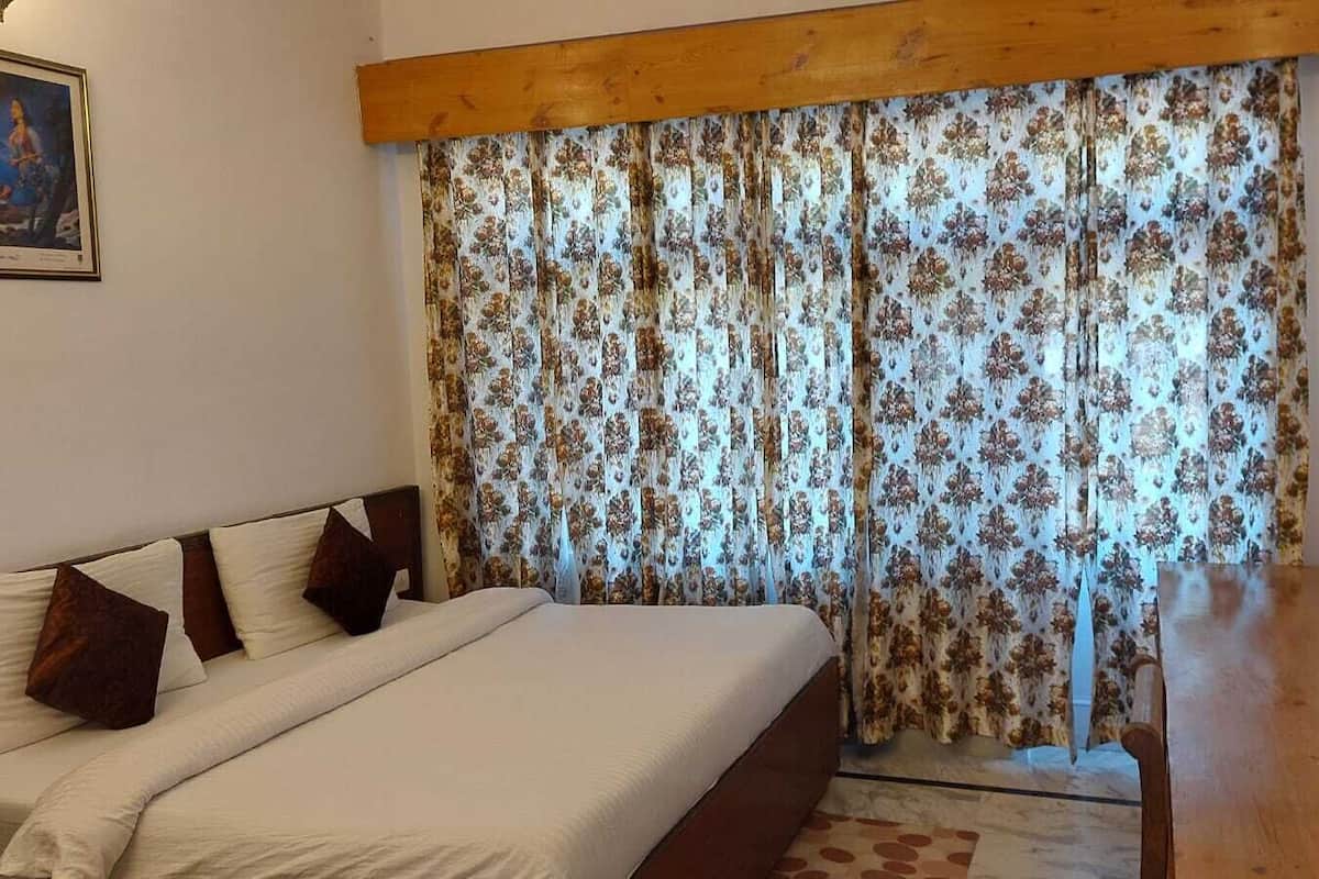 Een slaapkamer met een bed, een houten hoofdbord, een televisie op een standaard en een gordijn met een bloemendesign.