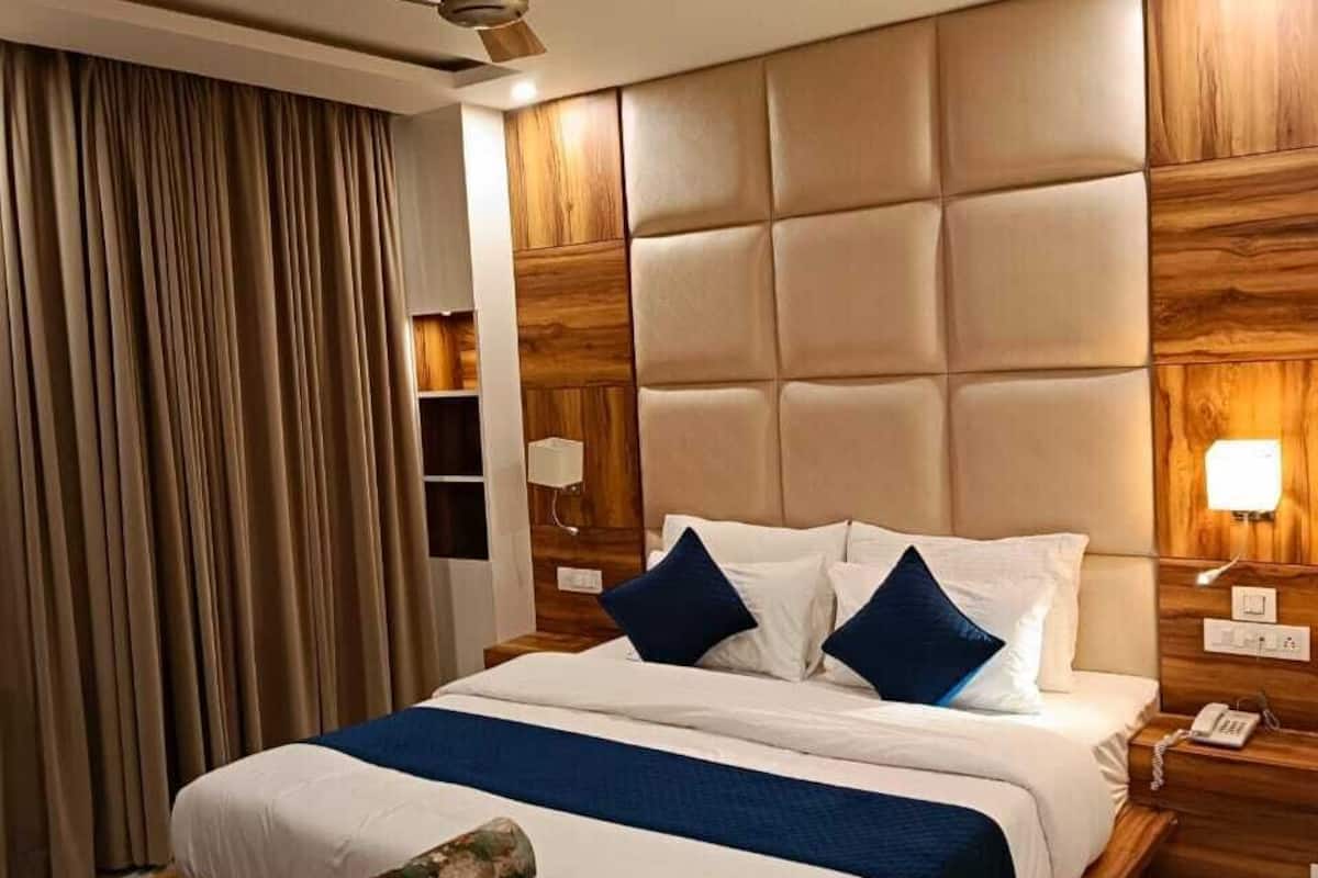 Een hotelkamer met een groot bed, een plafondventilator, een houten hoofdeinde en een fauteuil met bloemenprint.
