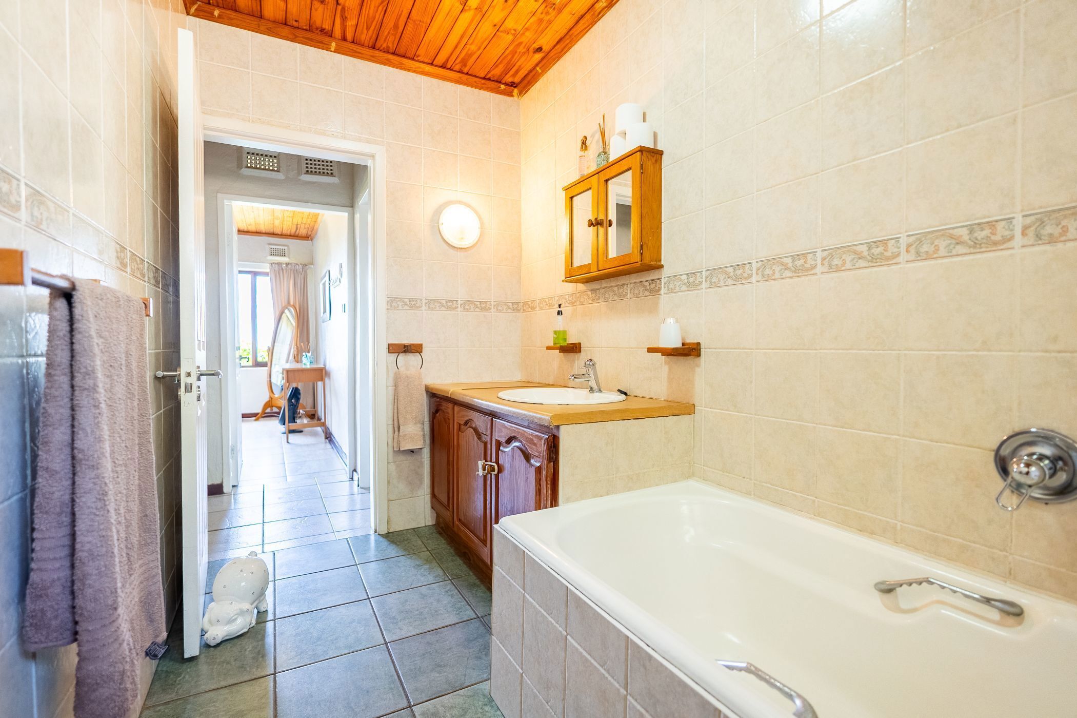 Une salle de bain avec une baignoire, un lavabo et un meuble en bois.