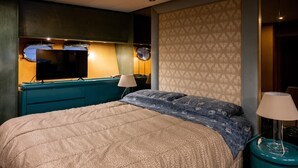 Een hotelkamer met een bed, een televisie, een lamp en een behang met een patroon.
