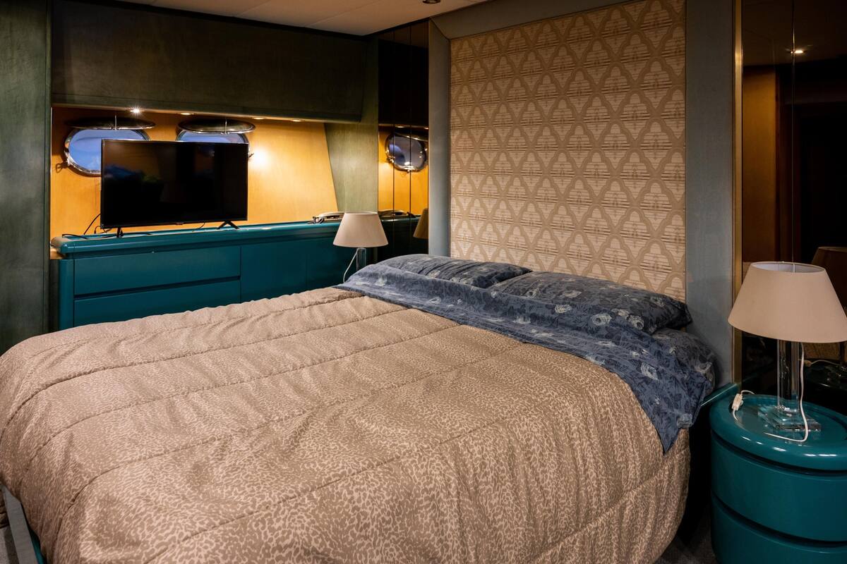 Ein Hotelzimmer mit Bett, Fernseher, Lampe und einer Wand mit Muster.