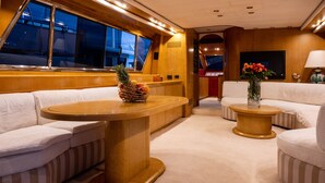 Een gezellig interieur met een houten tafel, gestreepte banken, een fruitmand en een bloevas.