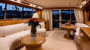 Een knus interieur met een bank, een ronde houten tafel en een raam met gordijnen.