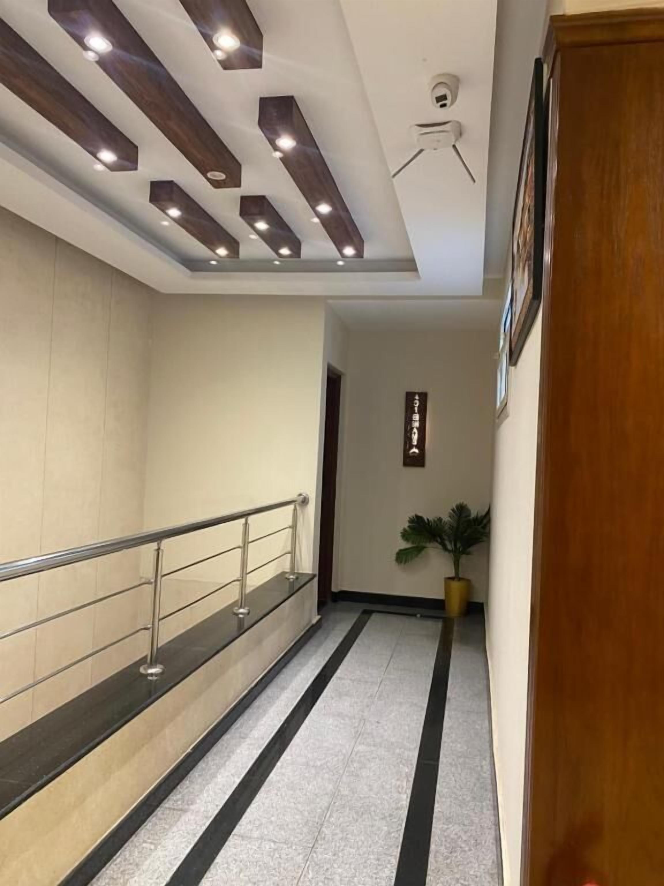 Un pasillo moderno con barandilla de vidrio, una planta en maceta y un cartel en la pared.