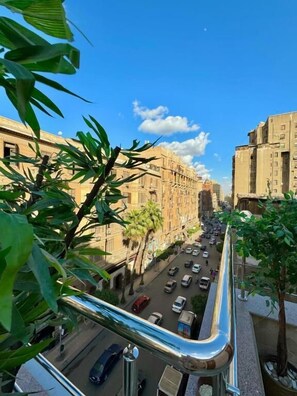A street view with buildings, cars, and palm trees. - Sun City Hotel (Cairo)