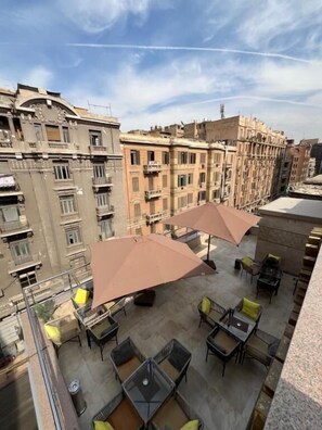 A rooftop terrace with outdoor seating and umbrellas, overlooking a cityscape with historic buildings. - Sun City Hotel (Cairo)