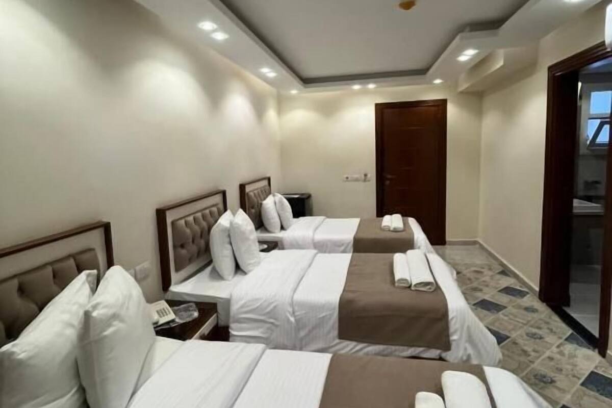 A hotel room with two beds, a wooden door, and a view of the outside.