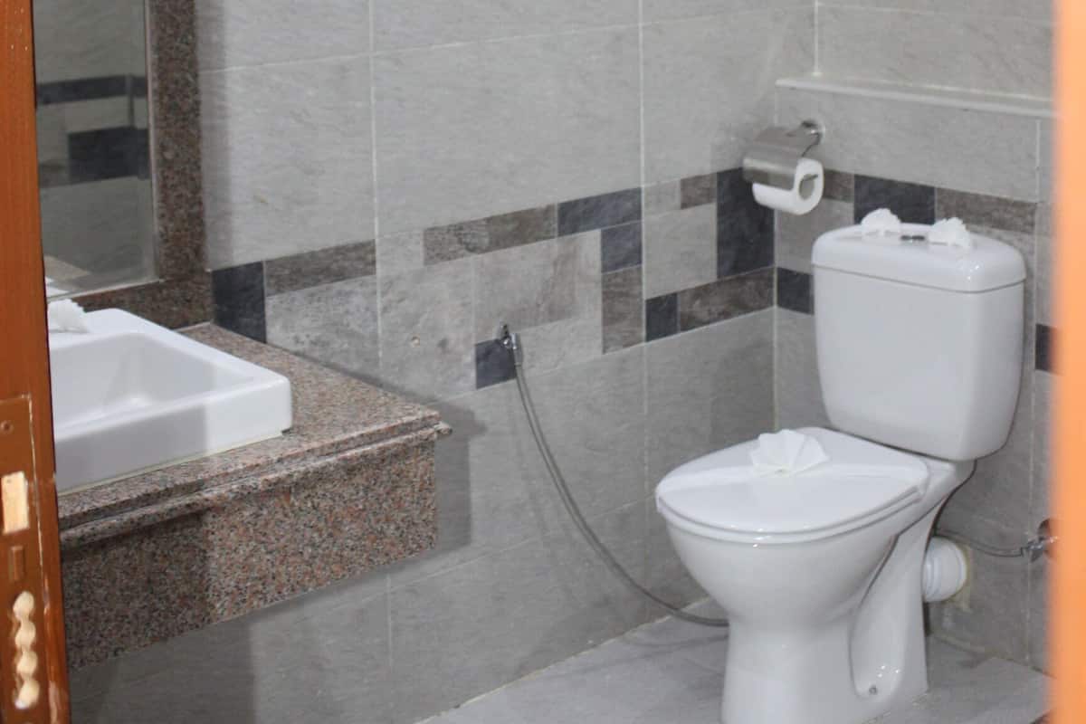A bathroom with a toilet, a sink, a shower, and a hand dryer.