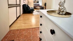 A hallway with a wooden floor leading to a living area with a sofa and a dining table. - Elegant Apartment on Hlavná Košice (Košický kraj)