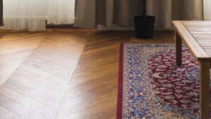 A room with a wooden floor, a potted plant, a table, and a patterned rug. - Trendy Apartment in Centrum 1 (Bratislavský kraj)