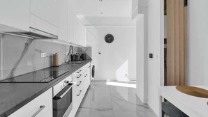 A modern kitchen with white cabinetry, a black countertop, and a built-in oven. - Trendy Apartment in Centrum 1 (Bratislavský kraj)
