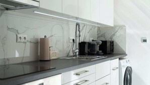 A modern kitchen with a marble backsplash, a coffee machine, and a washing machine. - Trendy Apartment in Centrum 1 (Bratislavský kraj)