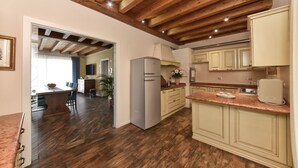 Una cocina con vigas de madera, un refrigerador y armarios de color claro.