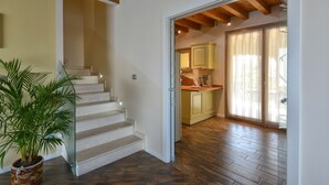 Una escalera conduce a una cocina con piso de madera y una planta en maceta.