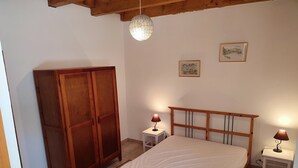 Een slaapkamer met een houten bed, een kledingkast, twee nachtkastjes met lampen en een hanglamp.