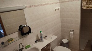 Een badkamer met wastafel, spiegel, toilet en douche.